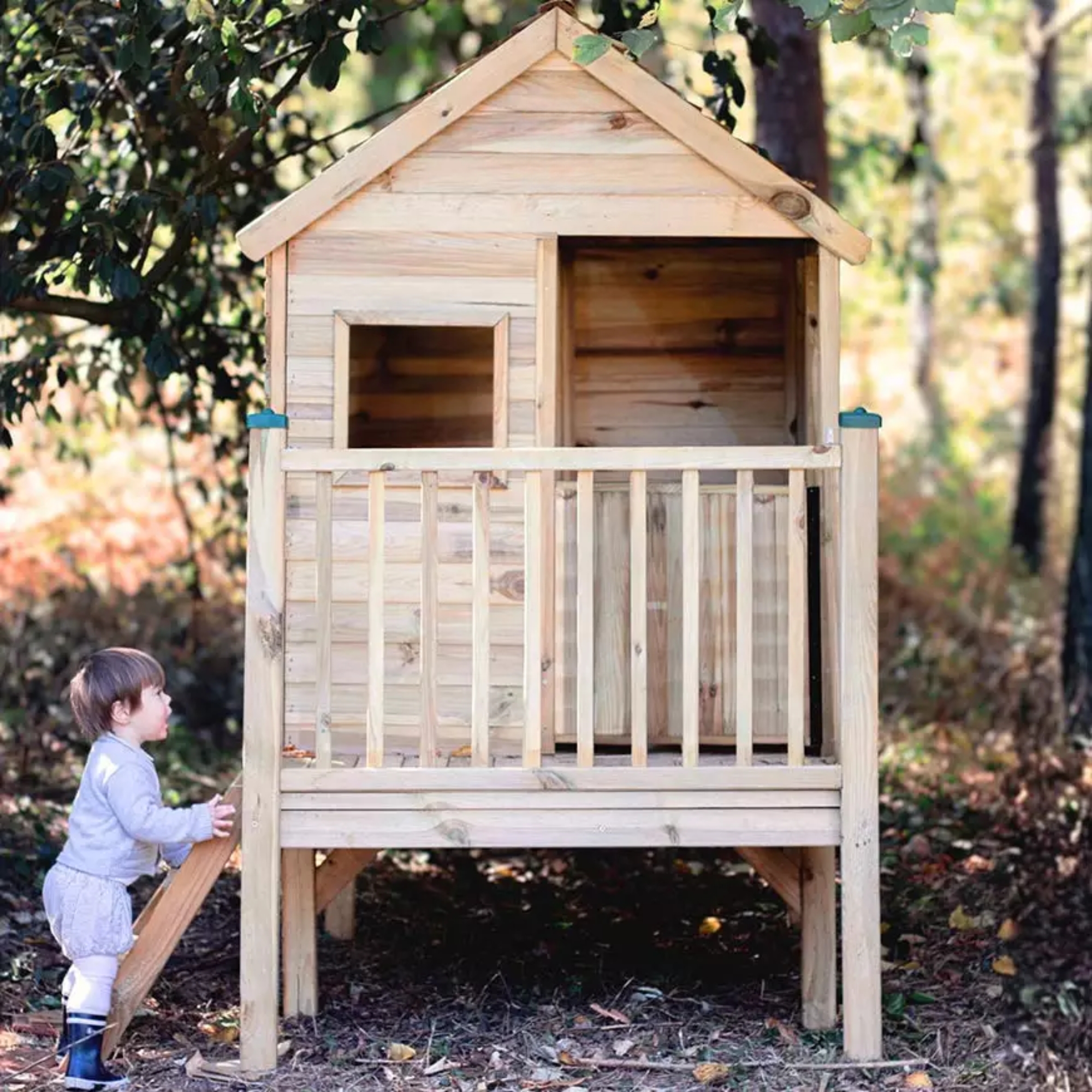 Cabane sur pilotis en bois traité marron Soulet avec toboggan dans un jardin